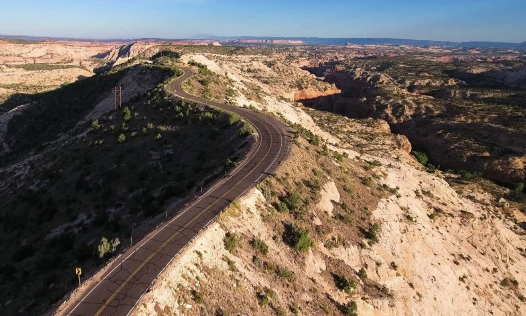 An aerial drone view of a two lane road curving along a ridge above a canyon on Scenic Byway 12