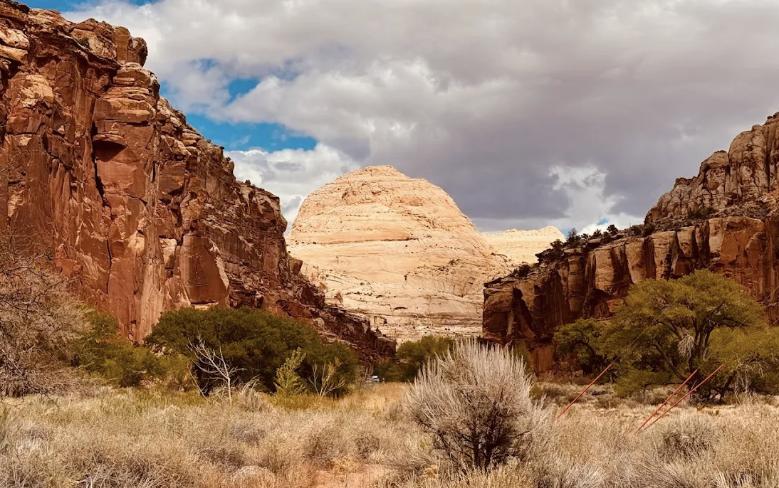 A large rounded white sandstone dome resembling Capitol Dome framed between red canyon walls in Capitol Reef National Park
