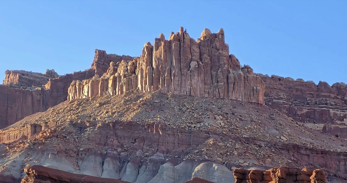 Tall narrow sandstone spires resembling the Castle formation rising from a talus slope in Capitol Reef National Park