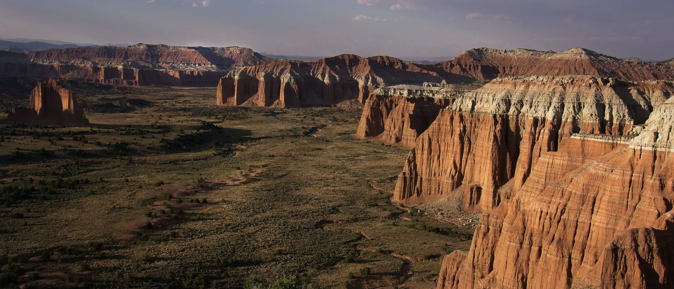 A wide panorama of red and white capped cliffs and monoliths across Cathedral Valley in Capitol Reef National Park