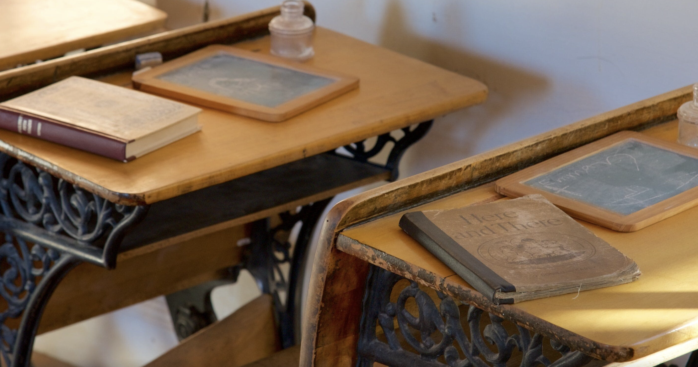 Antique wooden school desks with slates, an inkwell and old textbooks inside a preserved one room schoolhouse