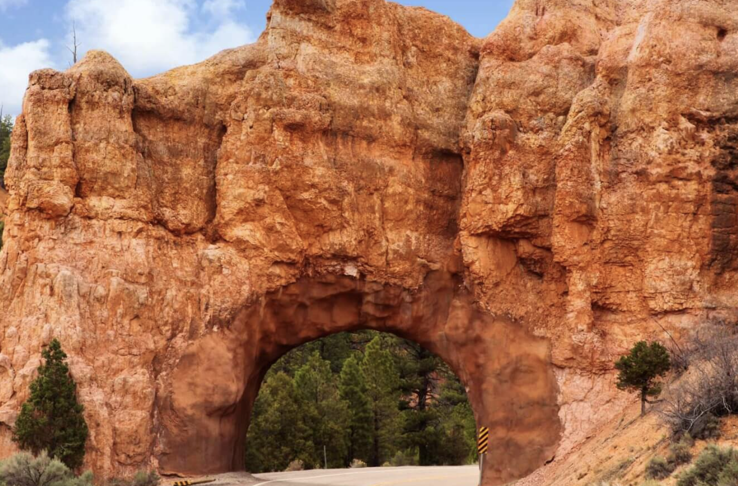A natural rock tunnel carved for the highway through red rock in Red Canyon along Scenic Byway 12