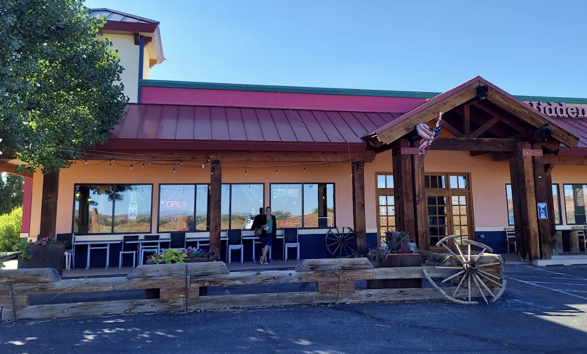 A restaurant patio with outdoor seating and wagon wheel decor along the road in Torrey, Utah