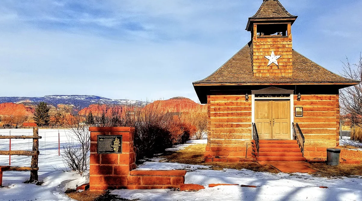The 1898 Torrey Log Church and Schoolhouse with its bell tower and star, snow on the ground, in Torrey, Utah