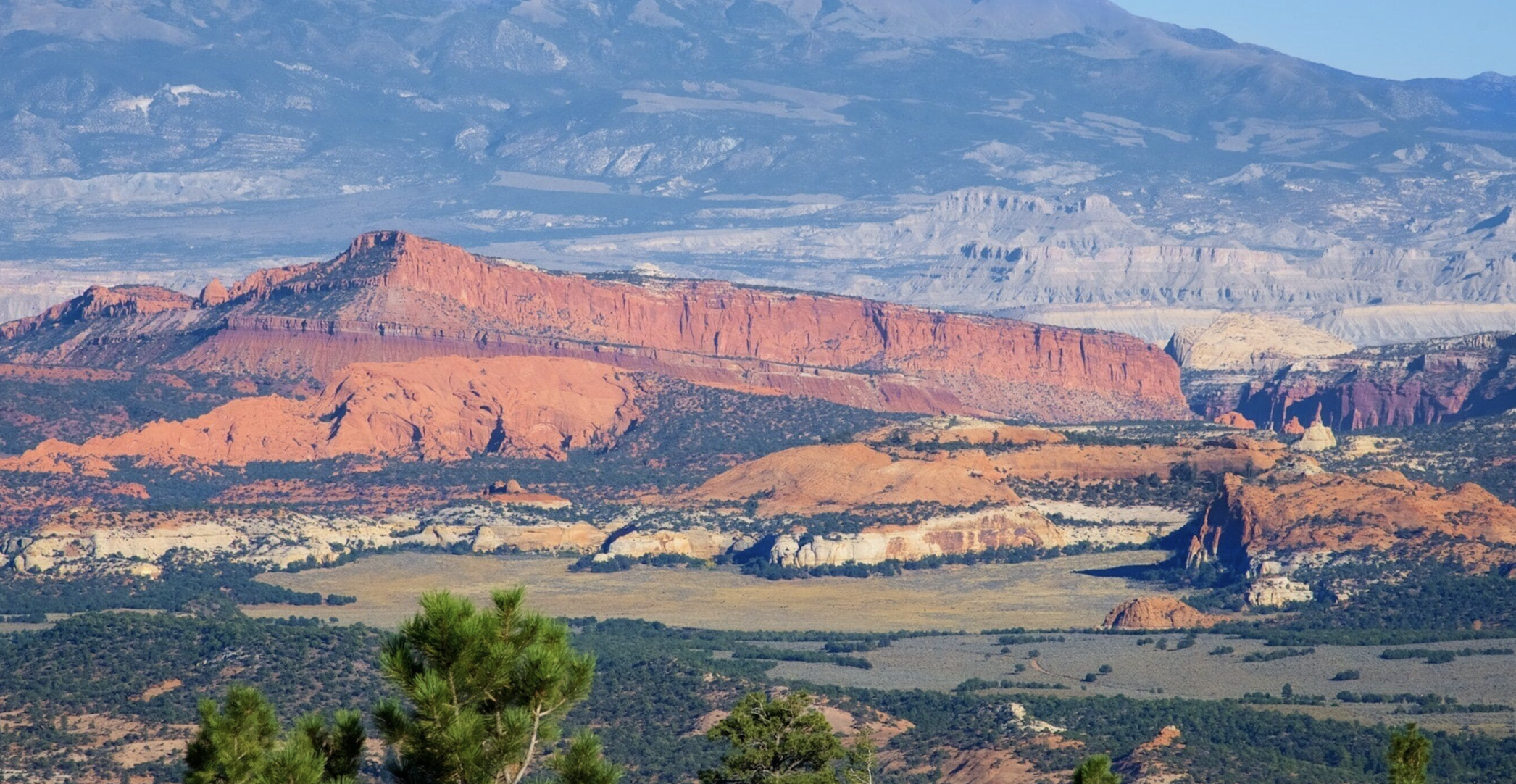 Red cliffs of the Waterpocket Fold with distant mountains rising behind in Capitol Reef country, Utah