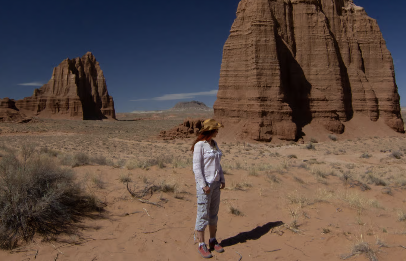 A woman standing near tall red rock monoliths in Cathedral Valley, Capitol Reef National Park